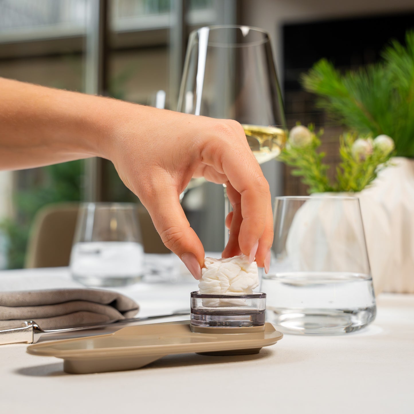 Hand legt TOWELLO Bloom Servierschale mit feuchtem Tuch auf Tisch bei elegantem Empfang in Hotelbar