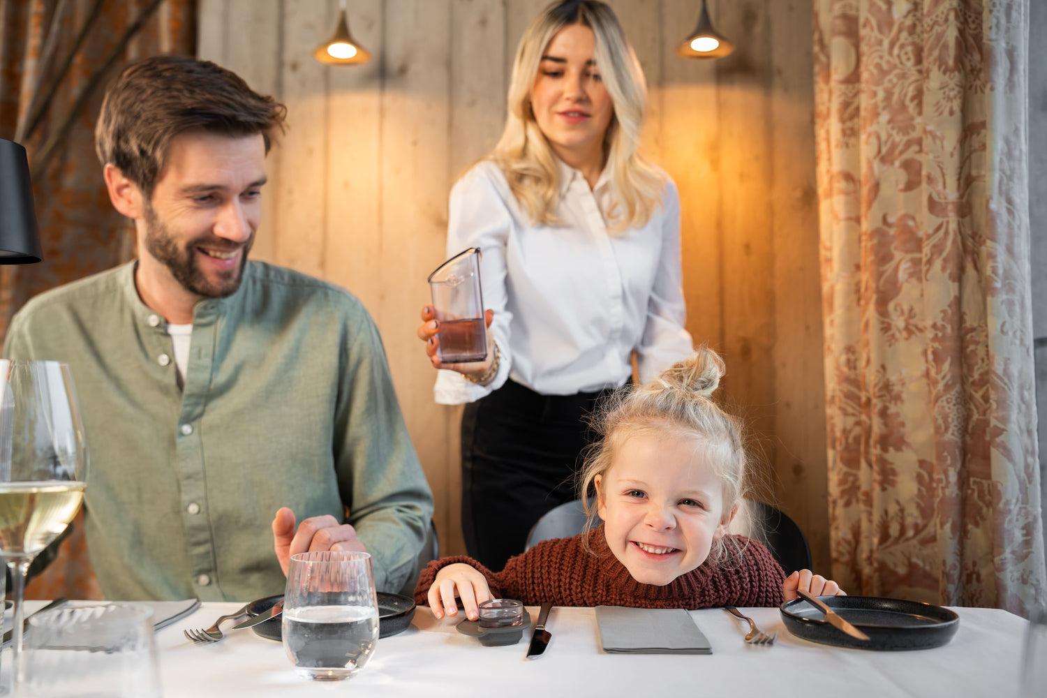 Mädchen freut sich auf Wasser, das von stilvoller Kellnerin in TOWELLO Oasis eingeschenkt wird 